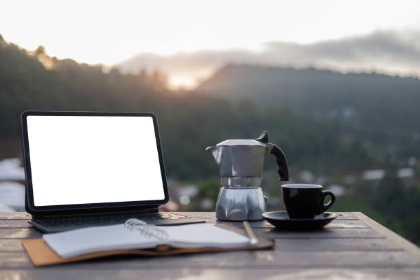 istock Computer laptop, moka pot and coffee cup on rustic wood table with mountain at morning background. 1403612469