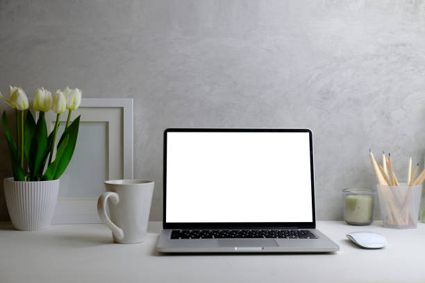 istock Home office interior. Computer laptop, picture frame, coffee cup, notebook and flower pot on white table. 1403612543
