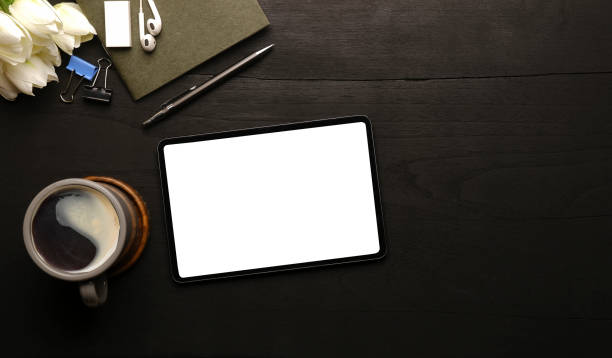 istock Flat lay digital tablet with empty screen, coffee cup and supplies on wood background. 1403612693