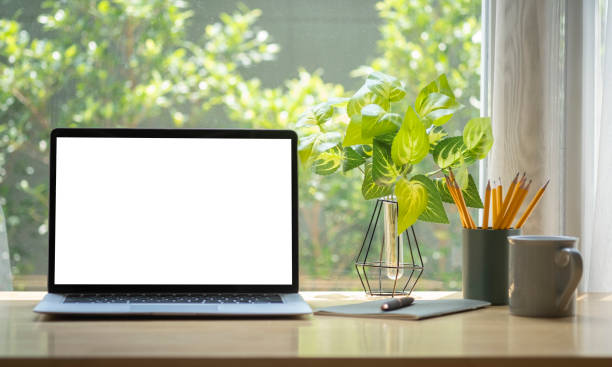 istock Computer laptop with empty display, coffee cup, pencil holder and houseplant on wooden table. 1403612879