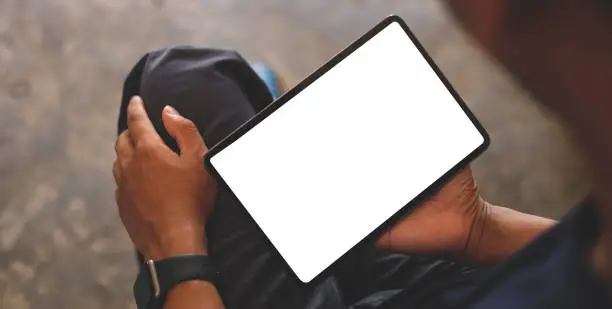 Photo of Man hands holding digital tablet with white screen.