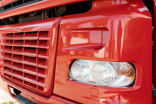 Closeup of front part of the red truck with radiator grille and headlight