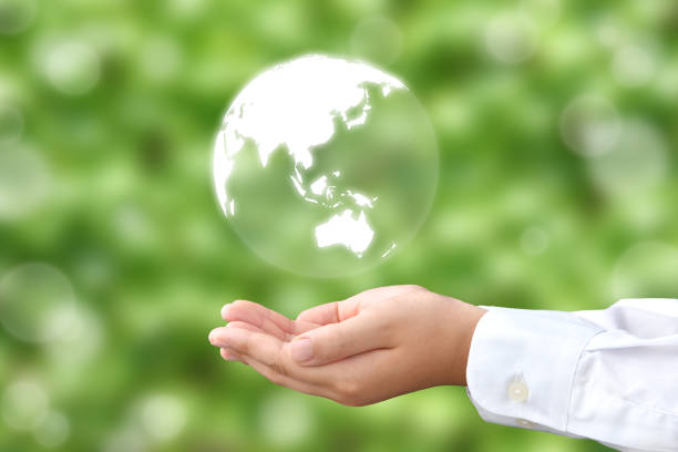 istock Child's hands covering earth object on natural green background 1403617504