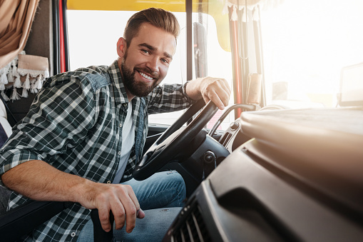 Portrait of young and happy smiling truck driver inside his vehicle