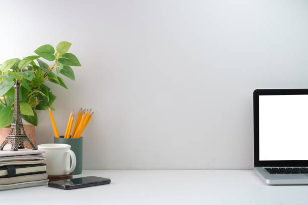 istock Minimal workplace with laptop computer, coffee cup, houseplant and stationery on white table. Copy space for your text. 1403618591