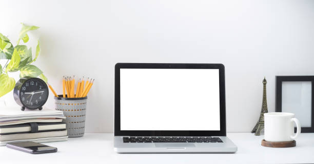 istock Mock up laptop computer, picture frame, coffee cup, books and pencil holder on white office desk. 1403619972