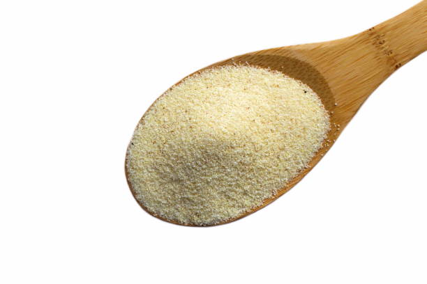 istock Semolina lies on a wooden spoon on a white background. 1403620056