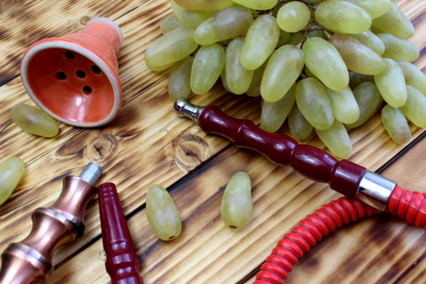 Details of a hookah with fruits lie on a wooden table.