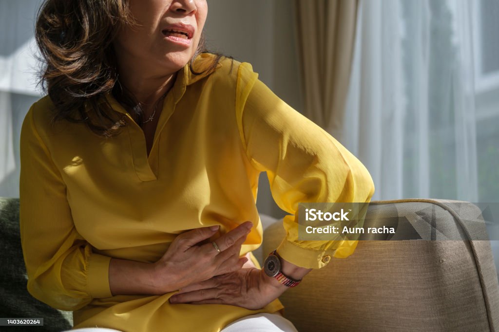Unhappy older lady putting hands on belly, having painful feeling in abdomen, suffering from strong stomach ache, gastritis symptom. Stomachache Stock Photo