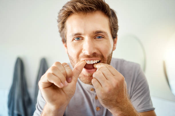 istock One handsome man flossing his teeth in a bathroom at home. Caucasian male using floss to prevent cavities while looking in a mirror in his apartment 1403621339