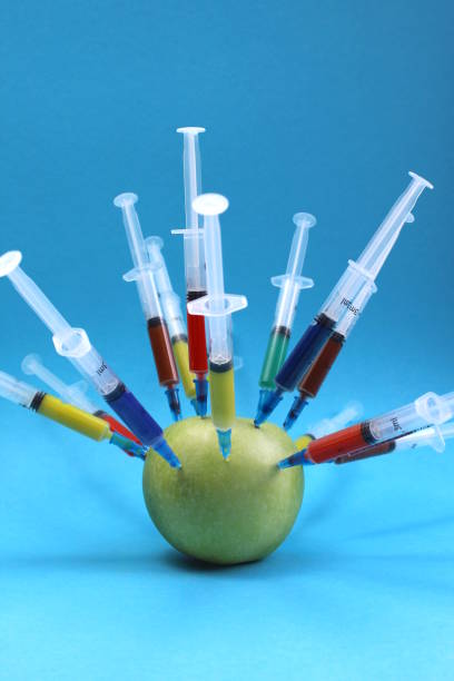 Many syringes with bright medicines are stuck in an apple. Many syringes with bright medicines are stuck in an apple. genetically modified food stock pictures, royalty-free photos & images