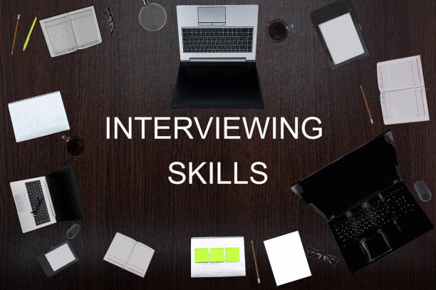 istock Top view of interviewing skills text on the table with laptops, notepad, coffee, eyeglasses, pens. Business concept. 1403622408