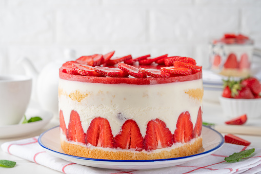 Fraisier mousse cake. Strawberry cake with biscuit, mousse and jelly on a white wooden background. Summer dessert. Selective focus. Copy space