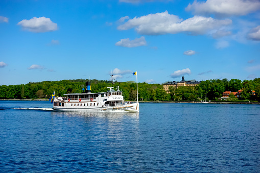 An old historical boat from Waxholmsbolaget travelling by Djurgården outside Stockholm, Sweden on a clear summer day