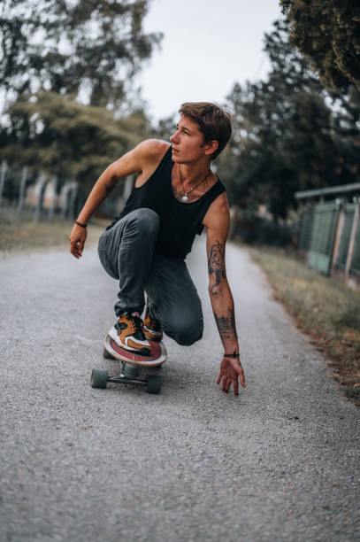 ein junger urbaner mann fährt mit seinem skateboard - longboard skating stock-fotos und bilder