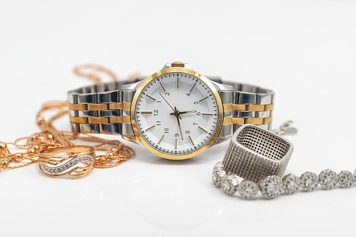 Gold and silver jewelry lies next to the original women's wristwatch