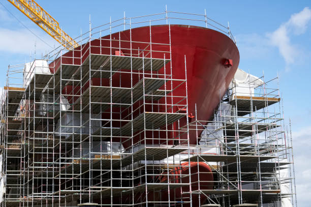 costruzione navale e gru durante la costruzione di traghetti circondati da impalcature - passenger ship ferry crane harbor foto e immagini stock