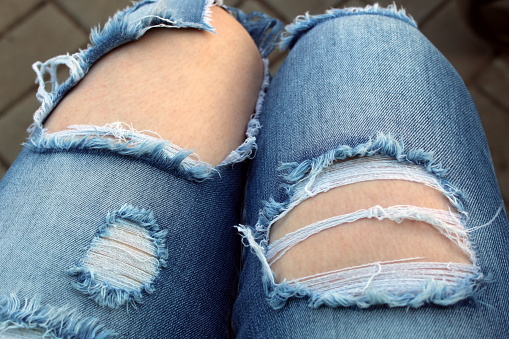 Ripped jeans on women's legs.