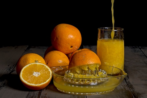 Glass orange juice squeezer with freshly squeezed juice being poured into glass
