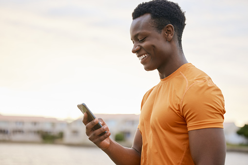 A fitness man looking at his phone smiling . An African American man in sportswear checking his smartphone.