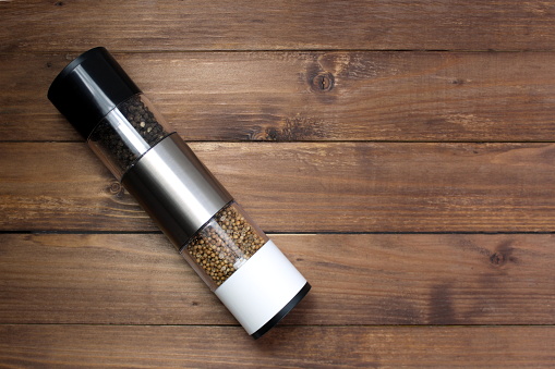 Spice grinder lies on a wooden background