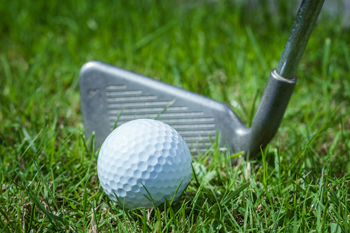 Golf ball with golf club on golf course, close up, no people,