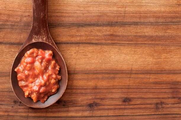 Top view of wooden spoon over table with meat and tomato sauce on it