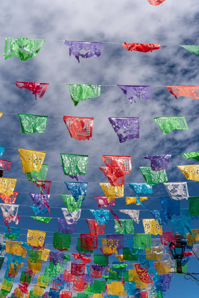 colorful mexican flags with a blue sky with clouds colorful mexican flags with a blue sky with clouds, celebration in mexico oaxaca city photos stock pictures, royalty-free photos & images