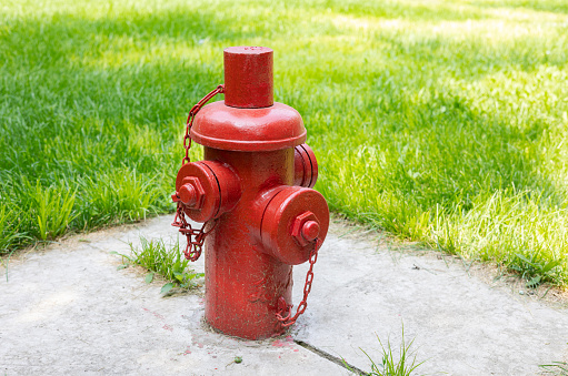 Iconic red fire hydrant against green grass and sidewalk