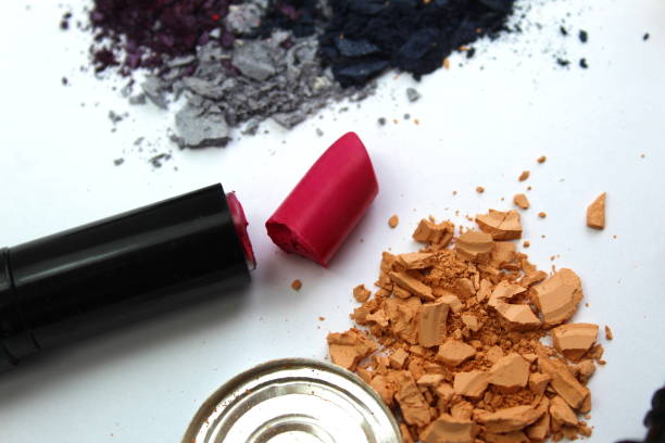 Different cosmetics, open, broken, scattered and spilled lies on a white background.