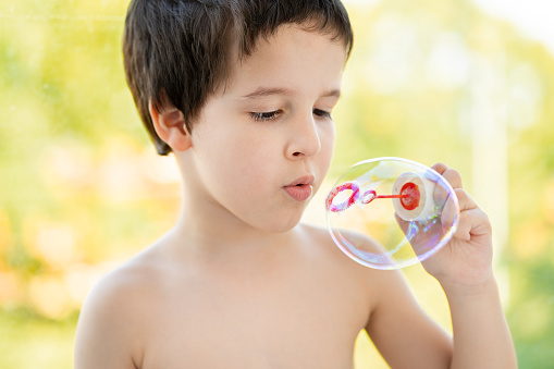 Little boy blowing bubbles in field