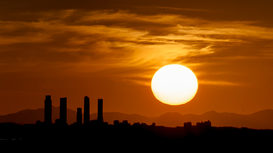 Sunset with an orange sky behind the skyline of the four towers of Madrid