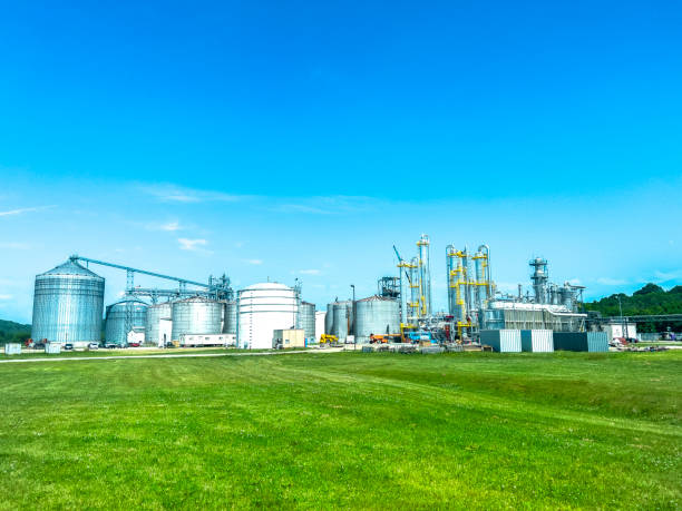 An Ethanol Refinery Plant An Ethanol refinery plant is surrounded by a green field and blue sky. The image features silos and buildings surrounded by lush greenery. ethanol stock pictures, royalty-free photos & images