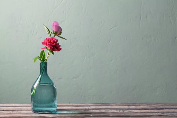 istock pink peonies in glass vase on green background 1403642863