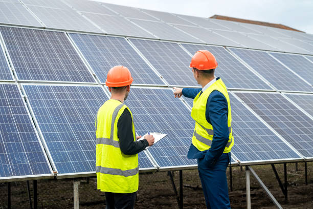 istock two young workers in overalls and helmets check the installed solar panels. 1403645058