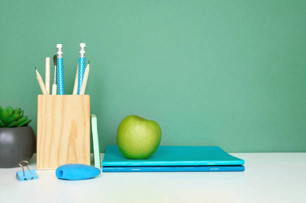 istock School equipment on white table, green wall background. Education backdrop. Wooden school supplies, notepad, pencils and cactus plant. Back to school. Student Desk . Stationery for study. Work at home 1403645470