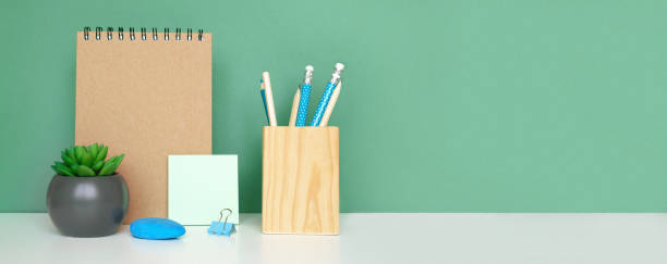 istock School equipment on white table, green wall background. Education backdrop. Wooden school supplies, notepad, pencils and cactus plant. Back to school. Student Desk . Stationery for study. Work at home 1403645551