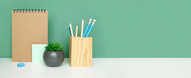 istock School equipment on white table, green wall background. Education backdrop. Wooden school supplies, notepad, pencils and cactus plant. Back to school. Student Desk . Stationery for study. Work at home 1403645562
