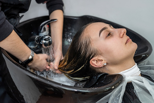 in an elite hairdresser's beautiful young woman washes her head in a special chair. The concept of washing the head in a beauty salon