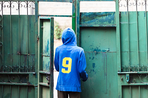 View of a Man wearing a hoodie with the number nine on the back at a steel fence