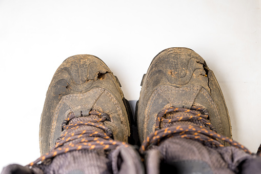 Shoes used in trekking in the field. Smoked shoes are torn at the tip. White background with space for text