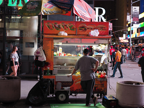 New York, USA - June 21, 2019: A vendor standing behind he's food stall near Times Square.