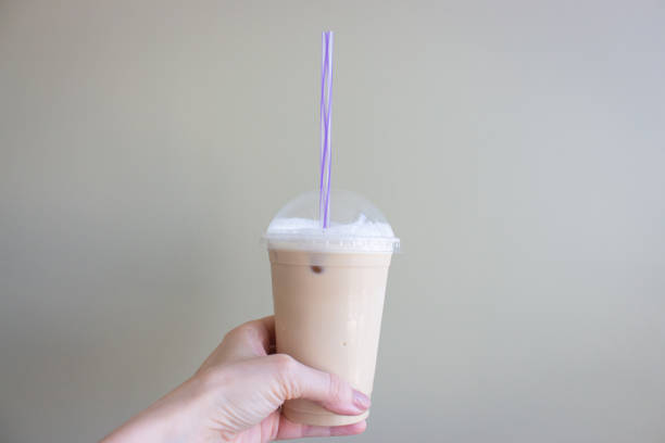 istock Iced coffee latte in hand. Coffee to go on wall background with copy space. Cold latte with drinking straw. Hand holding cold coffee. Breakfast drink. Summer drinks. 1403652802