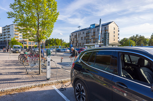 Sweden. Uppsala. 05.23.2022. View of connected charging cable to black car from an electric vehicle charging station.