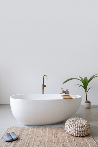 Classic white bathtub with copper faucet and decor in contemporary bathroom. Modern interior design. Home spa. Apartment coziness idea. Body care at home