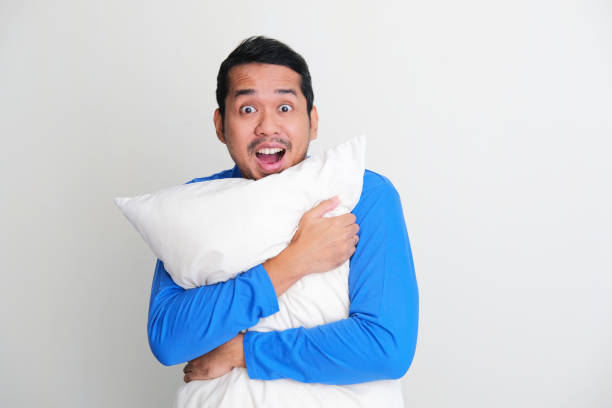 istock Adult Asian man hugging a pillow while showing happy face expression 1403659457