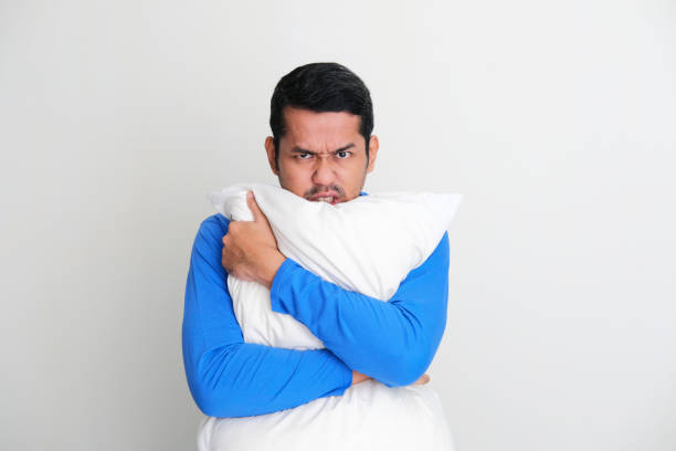 istock Adult Asian man hugging a pillow while showing angry face expression 1403659462