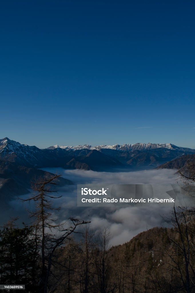 View on Kamnik-Savinja Alps over the foggy valley from Krvavec Ski Resort, Gorenjska Region, Slovenia Blue Stock Photo