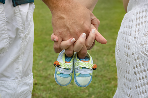 Close up of couple holding hands expecting their first child