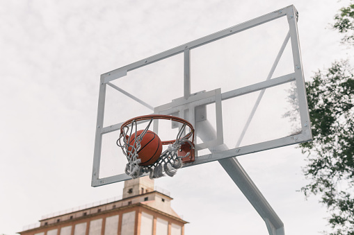 Glass or transparent plastic sports board to play basketball seen from below. Side and low angle view. Free throw or triple. Sport concept.